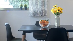 A dining table with a bowl of oranges and a vase of sunflowers. - Cozy Fully Renovated Studio in Holargos (Papagou-Holargos)
