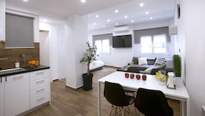A modern apartment with a kitchen, dining area, and living room. It features a large window, a flat-screen TV, and a potted plant. - Α Koukaki, Modern Newly Refurbished Apartment (Athens)