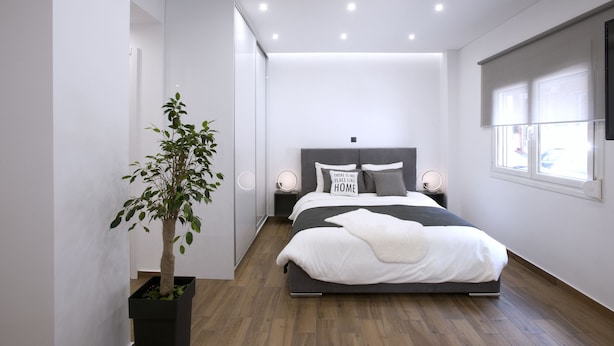 A modern bedroom with a bed, bedside lamps, a potted plant, and a window with blinds. - Α Koukaki, Modern Newly Refurbished Apartment (Athens)
