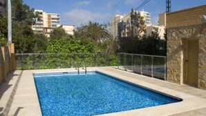 A rectangular swimming pool with a tiled edge, surrounded by a low stone wall and a metal fence. - Paraiso Florida (Benidorm)