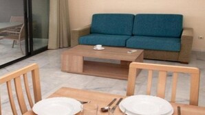 A modern room with a blue sofa, a wooden coffee table, and a dining table set with plates and cutlery. - Paraiso Florida (Benidorm)