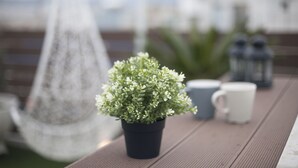 Une plante en pot, posée sur une table en bois, avec deux tasses et une lanterne.