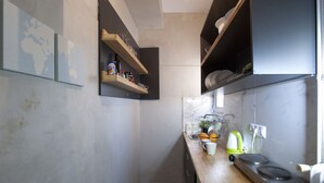 Une cuisine moderne avec des plans de travail en bois, un four encastré et une machine à café. On y trouve des étagères remplies d’ustensiles de cuisine et une carte du monde accrochée au mur.