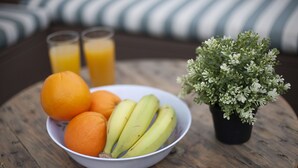 Un saladier rempli de fruits est posé sur une table en bois, à côté d’une plante en pot.