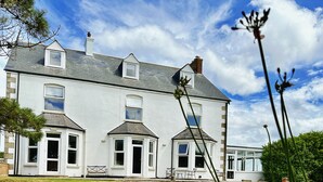 A large white building with multiple windows and a grassy yard. - St George's Hotel (Perranporth)