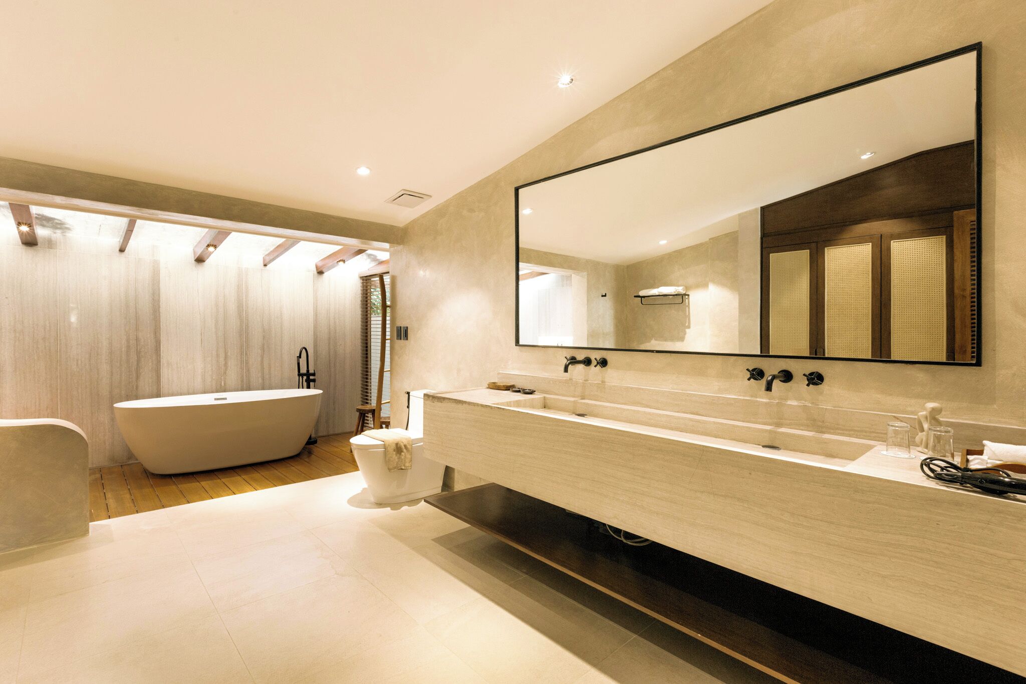 A modern bathroom with a freestanding bathtub, a large mirror, and a long vanity.