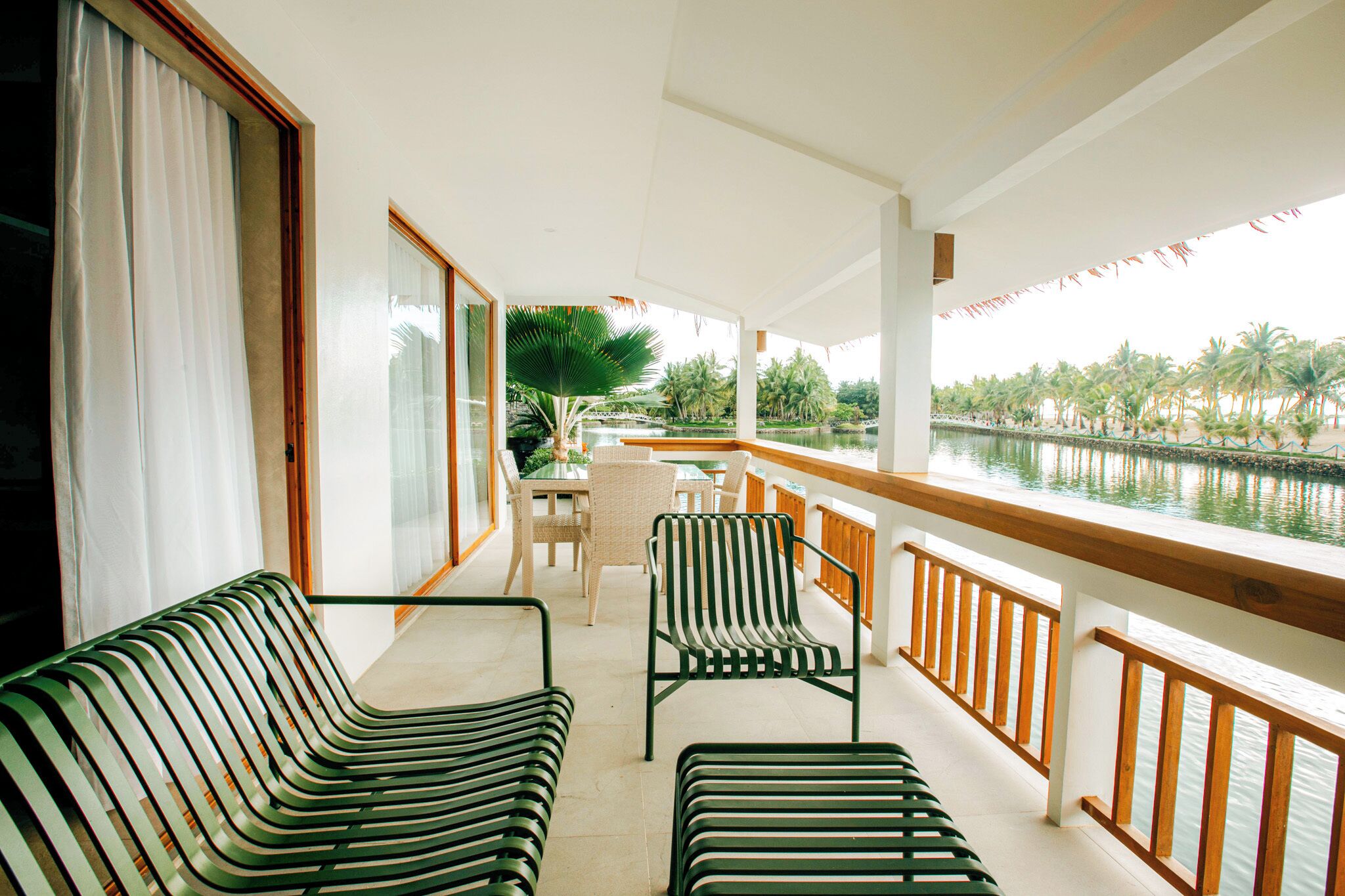 A balcony with a view of a water body, furnished with striped chairs and a table.