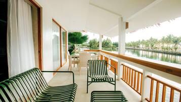 A balcony with a view of a water body, furnished with striped chairs and a table.