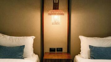 Habitación de hotel con dos camas, una mesita de noche, una lámpara de pared y un panel de control.