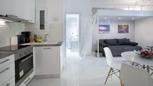 A modern kitchen with white cabinetry, a built-in oven, and a dining area with a white table and chairs. - Victoria Square, Cozy and Stylish Apartment (Athens)