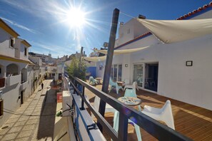 A sunny courtyard with a wooden deck, outdoor seating, and a view of the surrounding buildings. - Son of a Beach Hostel (Albufeira)