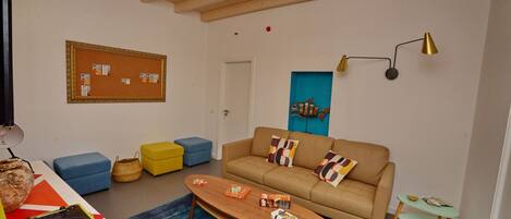 A living room with a wooden ceiling, a beige sofa, a blue rug, and a small table with a record player.