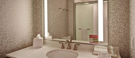 Un baño moderno con un espejo grande, un lavabo y una zona de ducha.