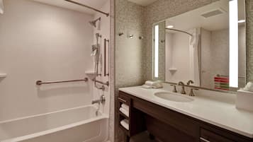 Une salle de bain moderne avec une baignoire, un grand miroir, un lavabo et un meuble-lavabo.