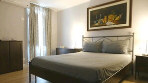 Un dormitorio con cama, mesita de noche, cómoda y un cuadro en la pared.