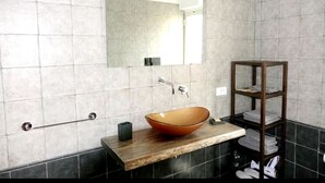 Un baño moderno con un espejo grande, un mueble de tocador de madera, un lavabo sobre encimera y un perchero para toallas.