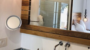 A bathroom with a white sink, wooden vanity, and a large mirror. There are two spherical pendant lights above the mirror. - Modern studio in Puerto Vallarta Down Town (Puerto Vallarta)