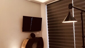 A modern room with a flat-screen TV mounted on the wall, a round black object on the floor, a rectangular black object, and a floor lamp. - Modern studio in Puerto Vallarta Down Town (Puerto Vallarta)