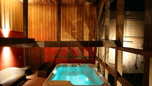 Una cabaña de madera con hidromasaje, paredes de madera y una pared de acento roja.