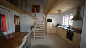 Una cocina con armarios de madera, una escalera y un comedor con mesa y sillas.