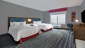A hotel room with two beds, a desk, a chair, a large window, and a radiator. - Hampton Inn Weslaco (Weslaco)