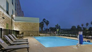 A pool area with lounge chairs, a pool, and palm trees. - Hampton Inn Weslaco (Weslaco)