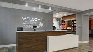 A hotel reception desk with a 'Welcome to the Lone Star' sign, a 'Hilton Honors' badge, and a 'Suite Shop' sign. - Hampton Inn Weslaco (Weslaco)