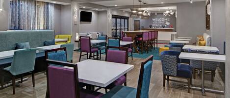 Un restaurant moderne avec des banquettes, des tables et des chaises aux couleurs vives.