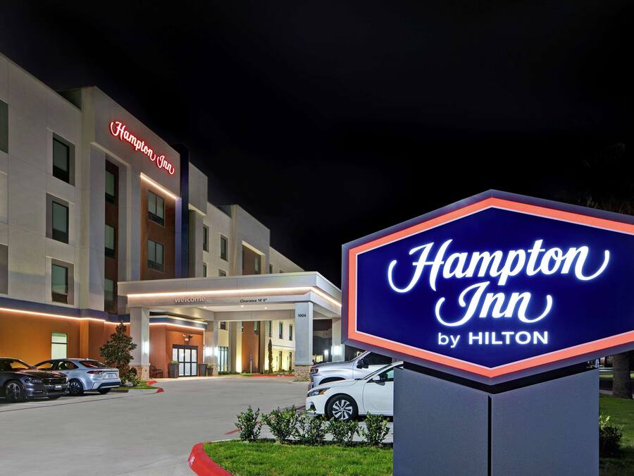 Un hotel Hampton Inn by Hilton de noche, con una entrada bien iluminada y una señalización clara.