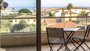 A balcony with a table and chairs, overlooking a residential area with houses and a clear sky. - ANTIBES - LARGE STUDIO BRIGHT, SEA VIEW for 4 pers (Antibes)