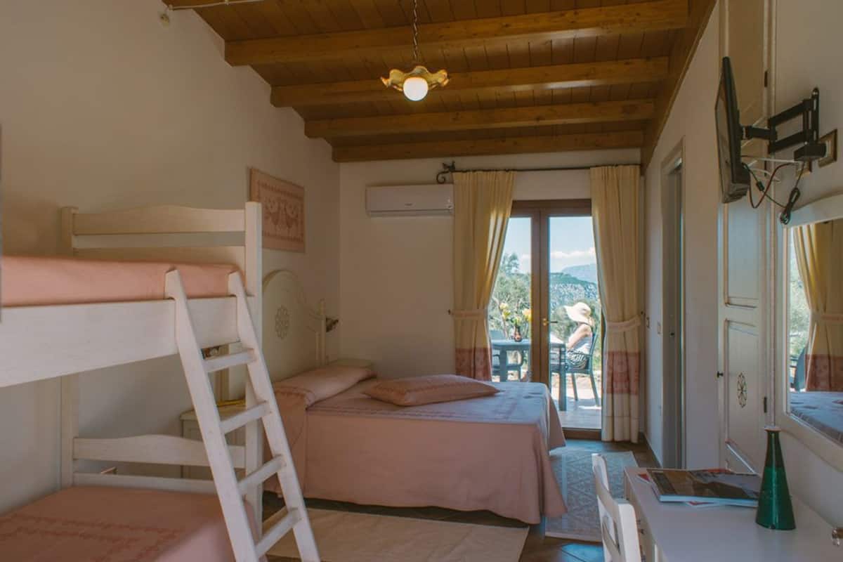 A bedroom with bunk beds, a wooden ceiling, an air conditioning unit, and a view of the outdoors.