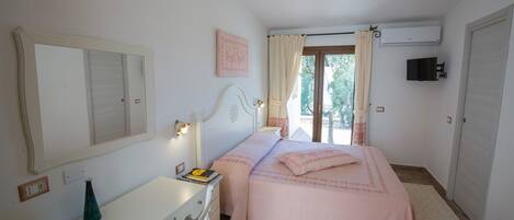 A bedroom with a bed, bedside table, dresser, and a window with curtains.