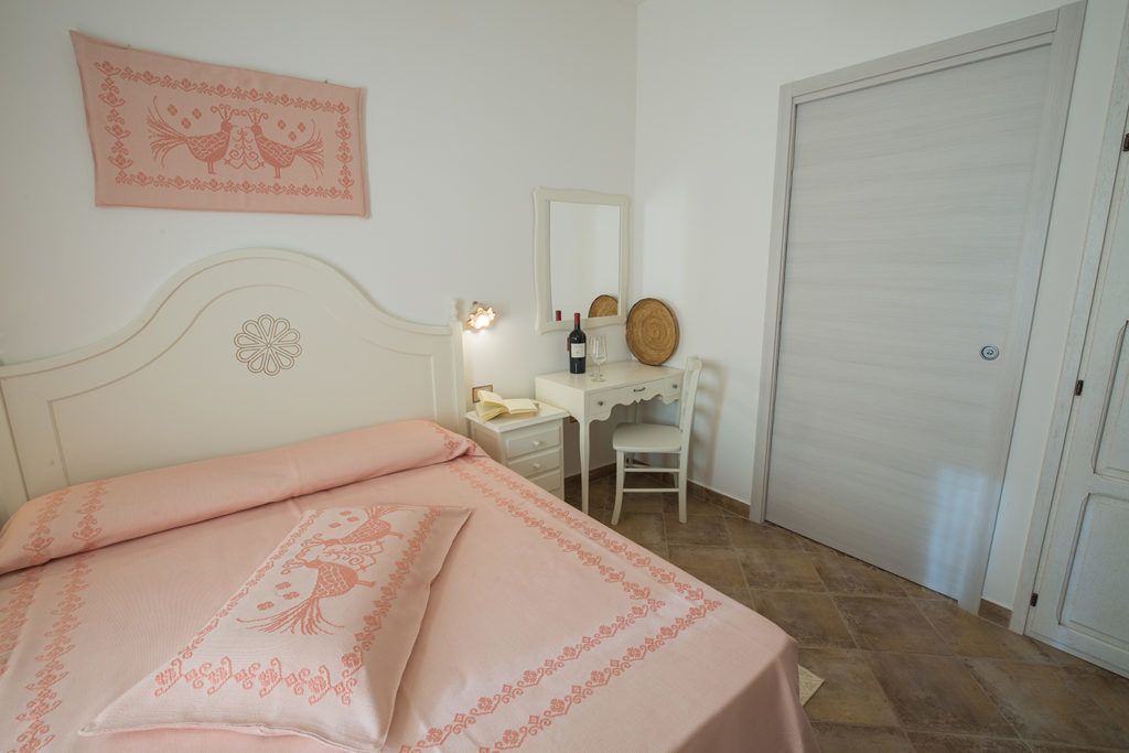 Un dormitorio con cama, escritorio, silla, espejo y armario.