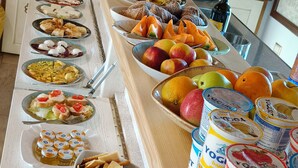 Un buffet con una varietà di cibi e bevande, tra cui frutta, pasticcini e yogurt.