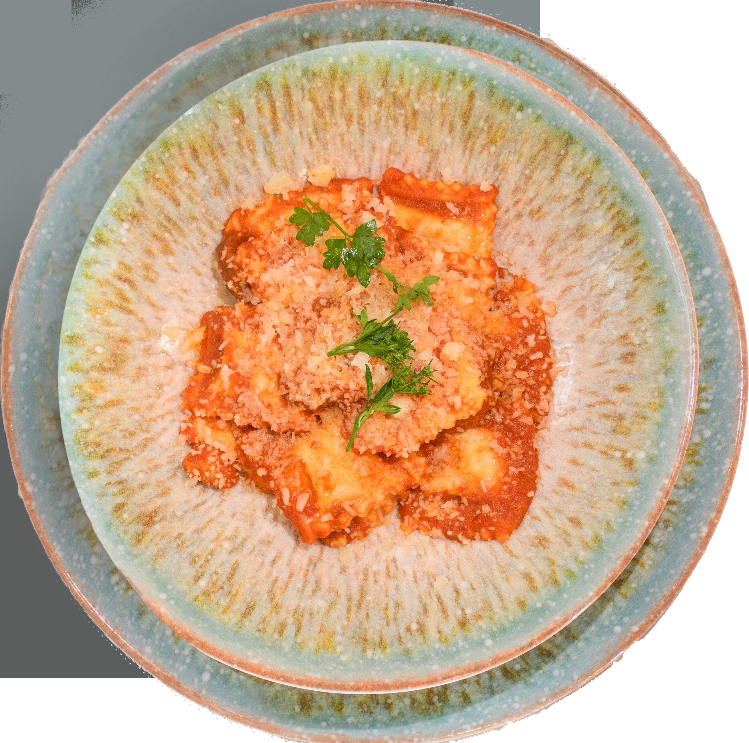 A plate of ravioli with a tomato-based sauce and a garnish of parsley.
