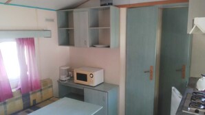 A compact kitchen with a microwave, coffee maker, and a small table. - Camping Manex - Mobil-Home (Saint-Pee-sur-Nivelle)