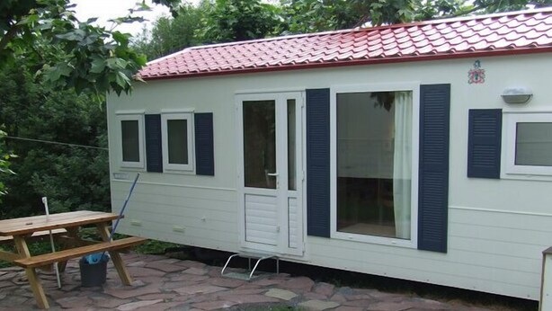 A mobile home with a red-tiled roof, a sliding door, and multiple windows with shutters. - Camping Manex - Mobil-Home (Saint-Pee-sur-Nivelle)