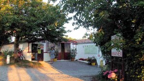 Un edificio rústico con un letrero que dice "MANEX" y un espacio cubierto al aire libre donde se ve una bicicleta estacionada.