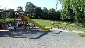Un parque infantil con un tobogán y columpios.