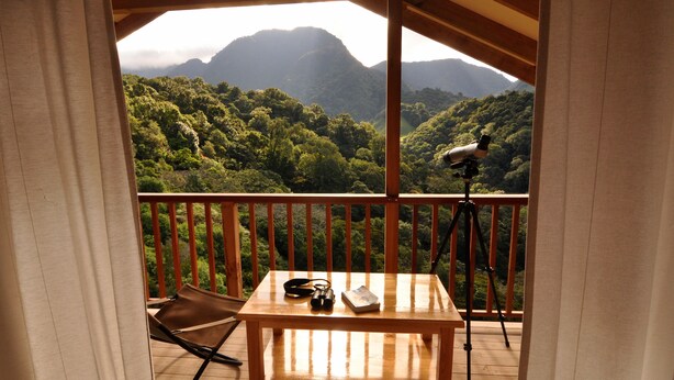 A wooden balcony with a table, a camera on a tripod, and a chair. - Mount Totumas Cloud Forest (Volcan)