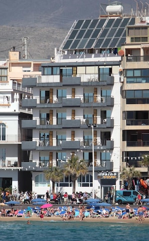 A multi-story hotel with balconies, a beach in the foreground, and a mountainous backdrop. - Hotel Bilbaino (Benidorm)