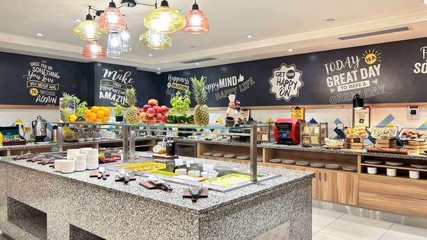 Zona de bufé con diversas opciones de comida y una pared decorativa con mensajes inspiradores.