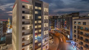 Un hotel moderno con un llamativo letrero de Hampton, varios pisos y una fachada distintiva con diseños geométricos.