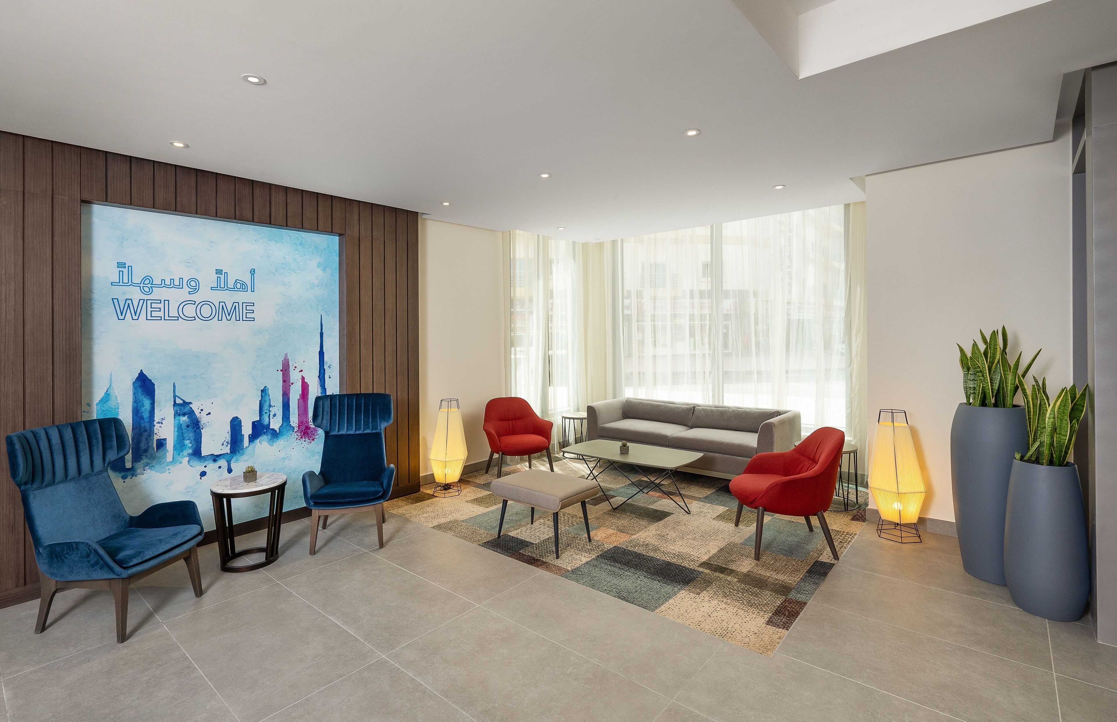 A modern lobby with a welcome sign, seating areas, and large windows.
