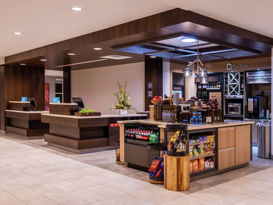 A modern coffee shop with a wooden counter, a refrigerated section, and a variety of snacks and beverages.
