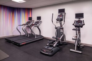 A fitness room with treadmills, elliptical machines, and stationary bikes, equipped with digital displays.