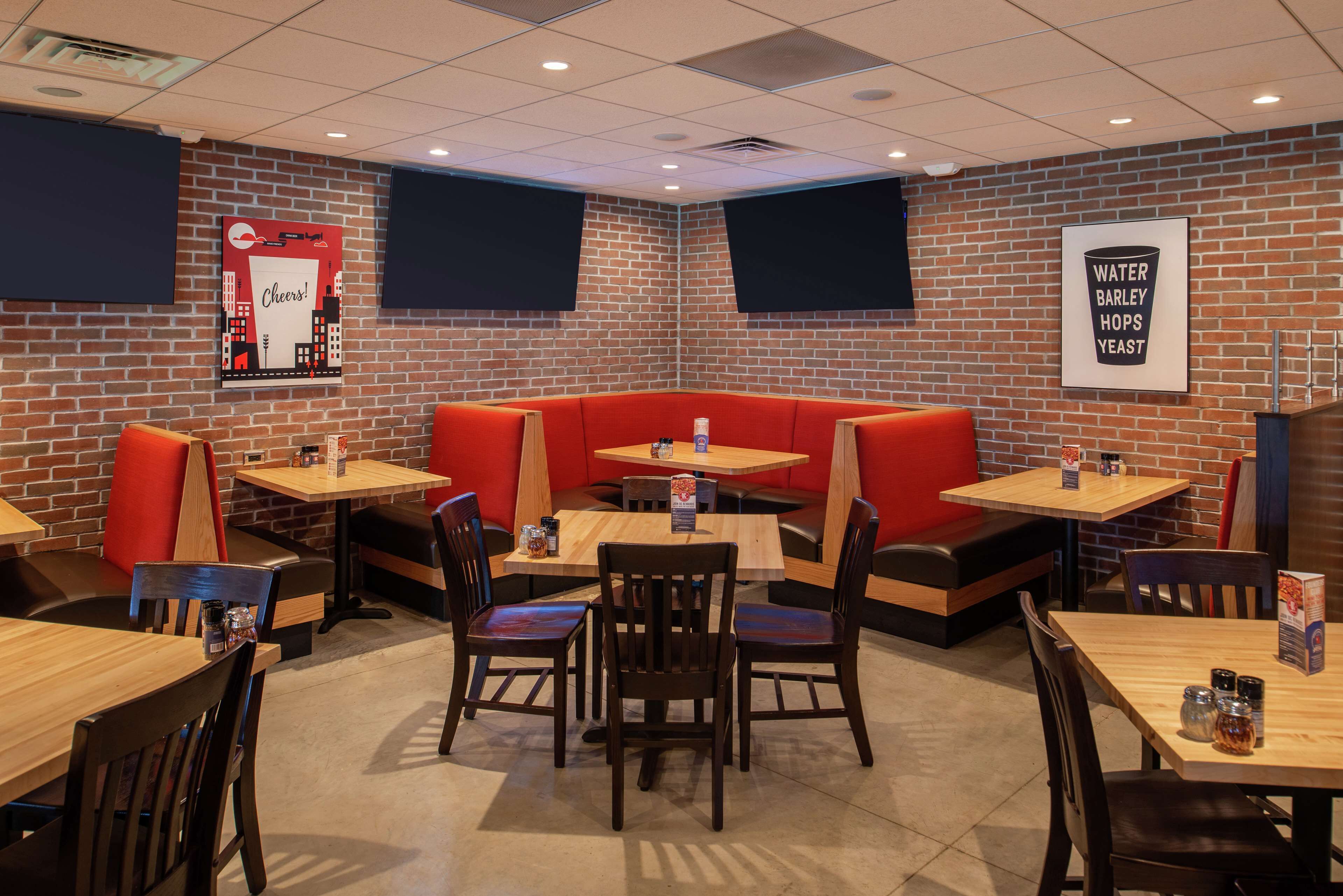 A restaurant with booths, tables, and a brick wall.