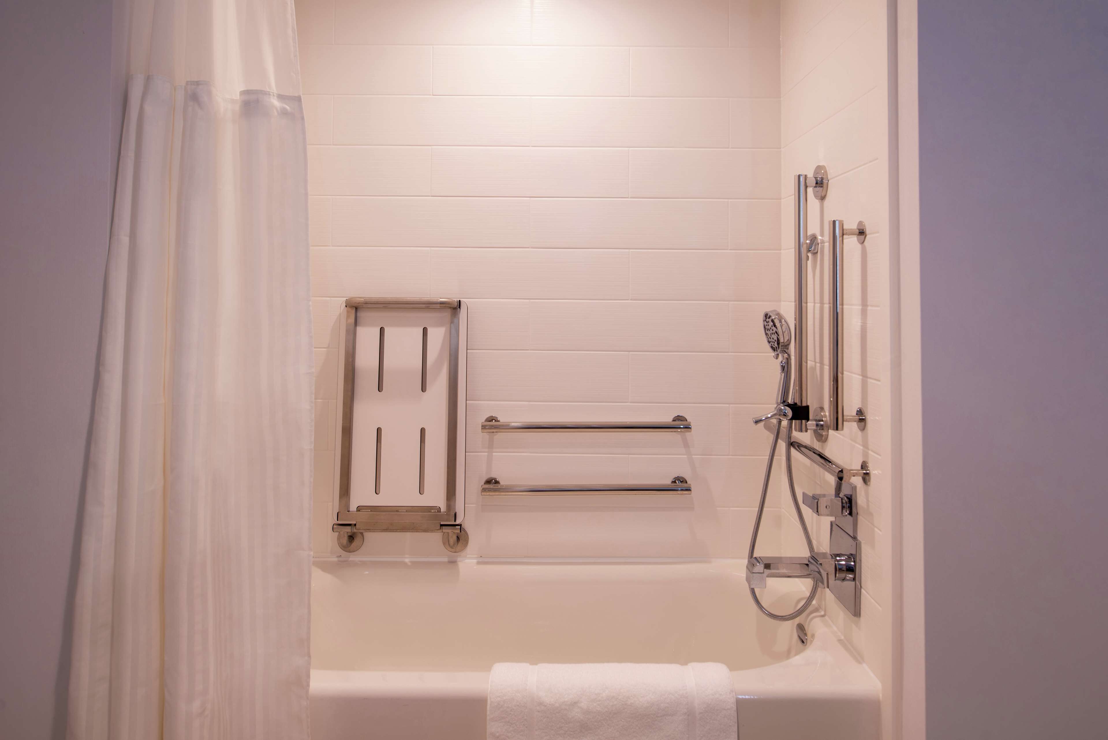 Un baño con bañera, ducha y barra para toallas.
