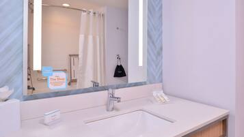 A modern bathroom with a large mirror, two sinks, and a shower.