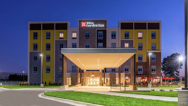A multi-story Hilton Garden Inn with a modern facade, a covered entrance, and a well-lit outdoor seating area. - Hilton Garden Inn Kansas City Airport (Kansas City)